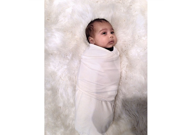 Baby North looks cute and cozy wrapped up on a fur carpet.